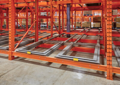 Close-up of a three-deep pushback racking system at Home Hardware, highlighting low-profile carts and double-posted front frames for impact protection.