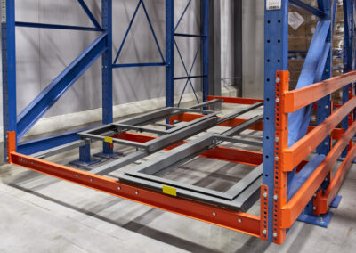 Three-deep structural pushback racking system in a food distribution warehouse, with offset front frames to protect against reach truck outrigger damage in a -25°C freezer.